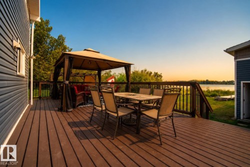 Expansive wood-finish deck with dark wood railings, offering a panoramic water backdrop - 264 Beach Avenue, Rural Barrhead County, AB - Outdoor With Deck Patio Veranda With Exterior
