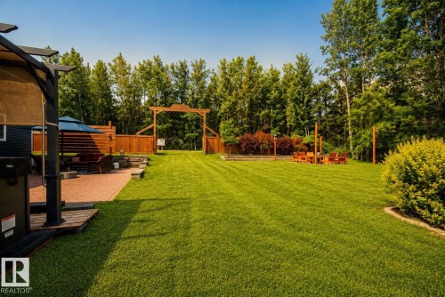 Expansive lawn with manicured landscaping, paved patio, and perimeter fencing - 264 Beach Avenue, Rural Barrhead County, AB - Outdoor