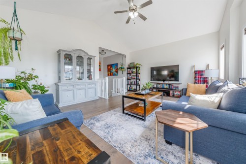 Vaulted ceiling with a ceiling fan, light wood-finish flooring, white wall paint, and a built-in display cabinet - 76 Dunlop Wynd, Leduc, AB - Indoor Photo Showing Living Room