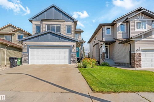 Two-story residence with a prominent gabled roofline, light-toned siding, and stone accents - 76 Dunlop Wynd, Leduc, AB - Outdoor With Facade