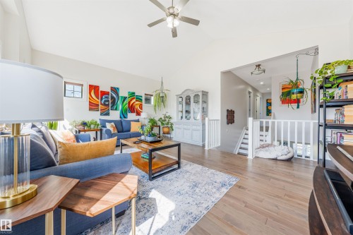 Vaulted ceiling with a ceiling fan, light wood-finish flooring, white railing, and multiple windows - 76 Dunlop Wynd, Leduc, AB - Indoor Photo Showing Living Room