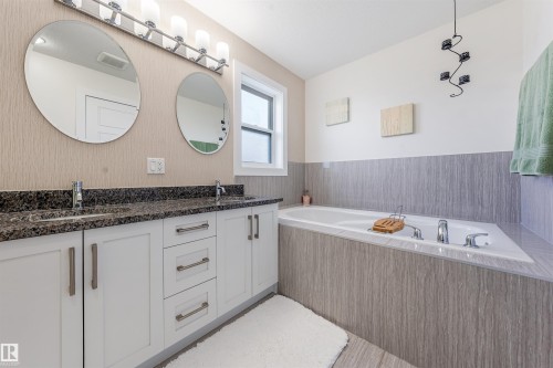Dual vanity with granite countertop, white cabinetry, and undermount sinks - 76 Dunlop Wynd, Leduc, AB - Indoor Photo Showing Bathroom