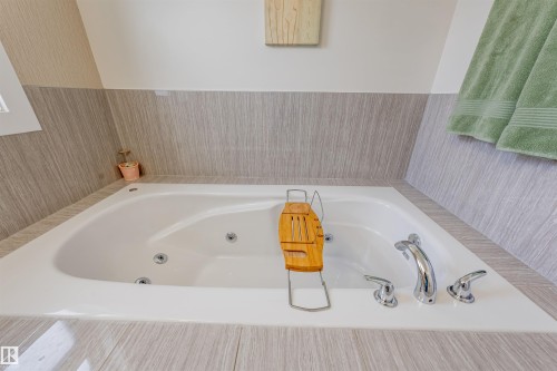 Built-in jetted tub with polished chrome fixtures and wood-look tile surround - 76 Dunlop Wynd, Leduc, AB - Indoor Photo Showing Bathroom