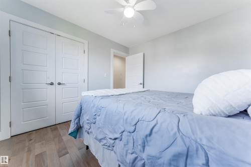 Recessed panel doors, wood-finish flooring, ceiling fan, and light gray wall paint - 76 Dunlop Wynd, Leduc, AB - Indoor Photo Showing Bedroom