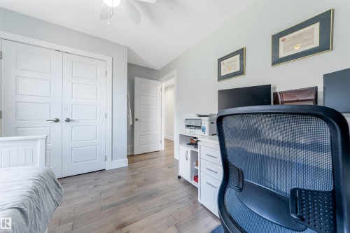 Wood-finish flooring, white paneled doors, ceiling fan with light fixture, and built-in white cabinetry - 76 Dunlop Wynd, Leduc, AB - Indoor