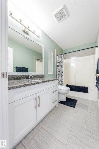 White shaker-style vanity with brushed nickel hardware, speckled countertop, and under-mount sink - 76 Dunlop Wynd, Leduc, AB - Indoor Photo Showing Bathroom