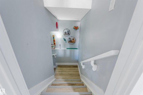 Staircase featuring wood-finish treads with safety strips, white handrails, and a built-in wall niche with shelving - 76 Dunlop Wynd, Leduc, AB - Indoor