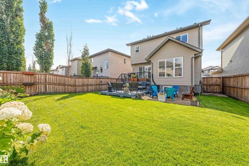 Expansive backyard featuring a manicured lawn, wood fencing, and a multi-level deck with black railing - 76 Dunlop Wynd, Leduc, AB - Outdoor With Backyard