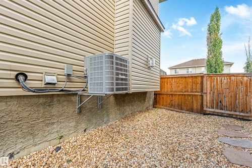 Exterior siding, stucco foundation, central air conditioning unit, wood fencing, and pea gravel landscaping - 76 Dunlop Wynd, Leduc, AB - Outdoor