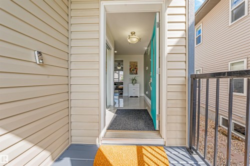 Beige horizontal siding exterior, vibrant turquoise entry door, black metal railing, and a covered entryway - 76 Dunlop Wynd, Leduc, AB - Outdoor With Exterior