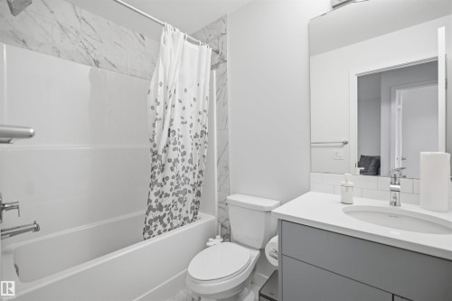 Tub and shower combination with tile surround, single vanity with integrated sink, and undermount cabinetry - 3877 Chrustawka Place Sw, Edmonton, AB - Indoor Photo Showing Bathroom