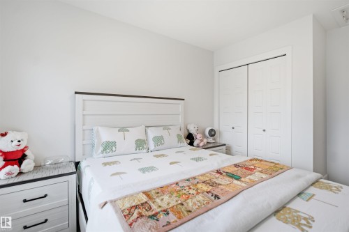 White paneled bi-fold closet doors, white shiplap headboard with dark trim, light-toned wood-finish nightstands with dark hardware, and bright white wall paint - 3877 Chrustawka Place Sw, Edmonton, AB - Indoor Photo Showing Bedroom