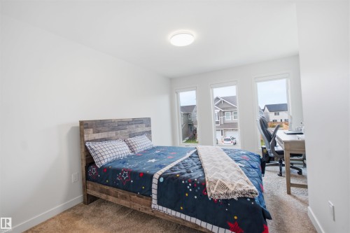 Clean white walls, three vertical windows, and a flush-mount ceiling light - 3877 Chrustawka Place Sw, Edmonton, AB - Indoor Photo Showing Bedroom