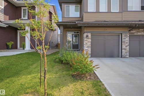 Contemporary exterior with stone accents, concrete driveway, and attached garage - 3877 Chrustawka Place Sw, Edmonton, AB - Outdoor With Facade