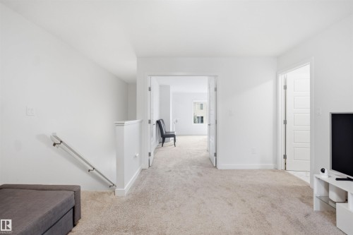Neutral-toned carpeting throughout, white wall finishes, and bright recessed lighting - 3877 Chrustawka Place Sw, Edmonton, AB - Indoor Photo Showing Other Room