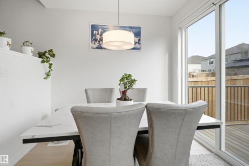 White walls with a decorative ledge, wood-finish flooring, and a sliding glass door - 3877 Chrustawka Place Sw, Edmonton, AB - Indoor Photo Showing Dining Room