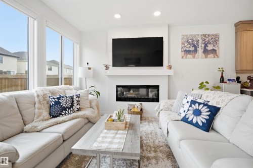 Living space featuring a built-in fireplace, recessed lighting, and large windows - 3877 Chrustawka Place Sw, Edmonton, AB - Indoor Photo Showing Living Room With Fireplace