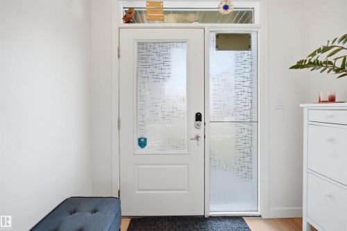 White entry door with decorative glass inserts, sidelight with patterned glass, and transom window - 3877 Chrustawka Place Sw, Edmonton, AB - Indoor Photo Showing Other Room