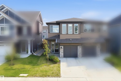 Two-story residence featuring a dual-tone exterior with stone accents, an attached two-car garage, and a concrete driveway - 3877 Chrustawka Place Sw, Edmonton, AB - Outdoor With Facade