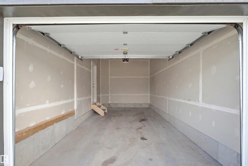 Unfinished garage interior featuring a concrete floor, concrete foundation, and partially finished drywall walls - 3877 Chrustawka Place Sw, Edmonton, AB - Indoor