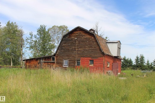 Barn structure with gambrel roof, red and natural wood siding, and surrounding grassy field - 49480 Rge Rd 41, Rural Leduc County, AB - Outdoor