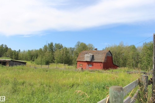 Red barn structure with a gambrel roof and dormer, surrounded by a wood fence - 49480 Rge Rd 41, Rural Leduc County, AB - Outdoor With View