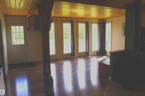 Wood-finish flooring, wood plank ceiling, exposed structural beam, multiple pane windows, and a glass-paneled exterior door - 49480 Rge Rd 41, Rural Leduc County, AB - Indoor Photo Showing Other Room