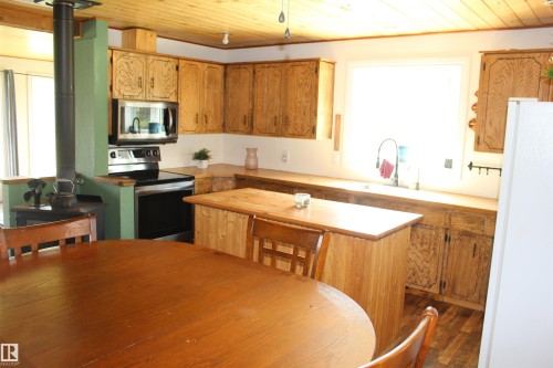 Kitchen featuring wood-finish cabinetry, stainless steel appliances, a wood-finish island, and wood-finish flooring - 49480 Rge Rd 41, Rural Leduc County, AB - Indoor