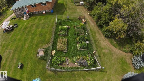Expansive fenced garden area with multiple raised beds, surrounded by a large grass lawn - 49480 Rge Rd 41, Rural Leduc County, AB - Outdoor