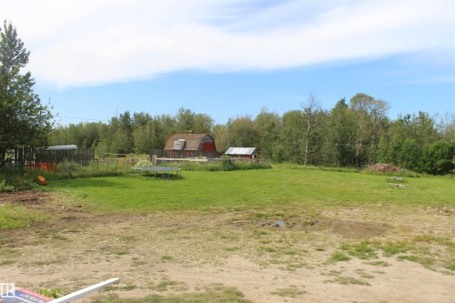 Expansive grassy area featuring a red barn structure, an additional outbuilding, and mature trees lining the property boundary - 49480 Rge Rd 41, Rural Leduc County, AB - Outdoor