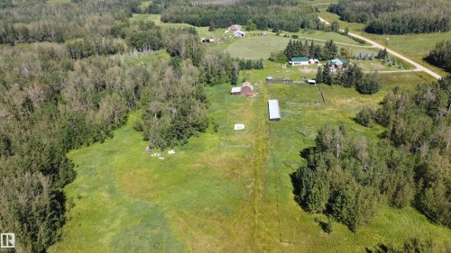 Extensive acreage featuring a primary residence with a green roof, multiple outbuildings, and a surrounding treeline - 49480 Rge Rd 41, Rural Leduc County, AB - Outdoor With View