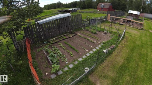 Enclosed garden area with cultivated beds, square stepping stones, and a surrounding wire fence - 49480 Rge Rd 41, Rural Leduc County, AB - Outdoor