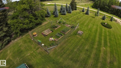 Expansive green lawn with mature trees and a fenced garden area featuring raised beds - 49480 Rge Rd 41, Rural Leduc County, AB - Outdoor With View