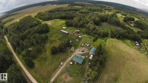 Extensive property featuring a gravel driveway, multiple structures with green roofing, and surrounding mature woodlands - 49480 Rge Rd 41, Rural Leduc County, AB - Outdoor With View