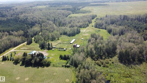 Expansive property featuring dense wooded areas, open fields, multiple outbuildings, and a main residence with a green roof - 49480 Rge Rd 41, Rural Leduc County, AB - Outdoor With View