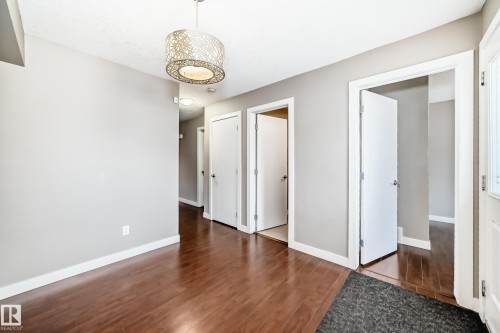 Entryway featuring wood-finish flooring, light grey walls, white trim, and multiple white doors - 12118 125 Street Nw, Edmonton, AB - Indoor Photo Showing Other Room