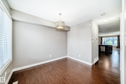 Dining area featuring wood-finish flooring, a contemporary pendant light fixture, and a large window with horizontal blinds - 12118 125 Street Nw, Edmonton, AB - Indoor Photo Showing Other Room