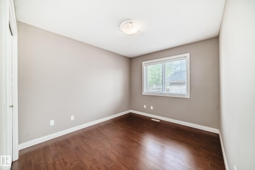 Room featuring wood-finish flooring, neutral wall tones, white trim, a large window with blinds, and a ceiling-mounted light fixture - 12118 125 Street Nw, Edmonton, AB - Indoor Photo Showing Other Room