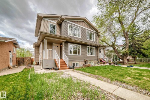 Multi-level property exterior featuring horizontal and shake siding, multiple windows with white trim, a covered porch with white railings, and a concrete pathway leading to the entrance - 12118 125 Street Nw, Edmonton, AB - Outdoor