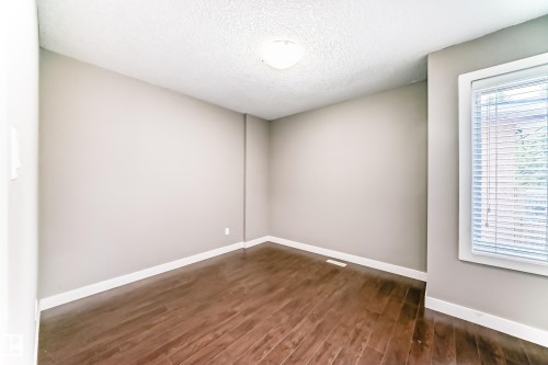 Room featuring wood-finish flooring, neutral wall paint, white trim, a flush-mount ceiling light, and a window with blinds - 12118 125 Street Nw, Edmonton, AB - Indoor Photo Showing Other Room