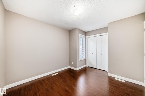 Room featuring wood-finish flooring, neutral wall tones, white trim, a window with blinds, and bi-fold closet doors - 12118 125 Street Nw, Edmonton, AB - Indoor Photo Showing Other Room