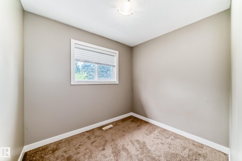Compact room featuring a single window with white trim, tan walls, and brown carpet flooring - 12118 125 Street Nw, Edmonton, AB - Indoor Photo Showing Other Room