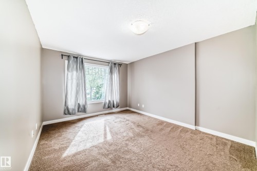 Spacious room featuring neutral paint, clean carpeting, crisp white baseboards, and a large window with natural light - 12118 125 Street Nw, Edmonton, AB - Indoor Photo Showing Other Room