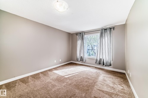 Neutral-toned room featuring a single window with white trim, brown patterned carpeting, and white baseboards - 12118 125 Street Nw, Edmonton, AB - Indoor Photo Showing Other Room