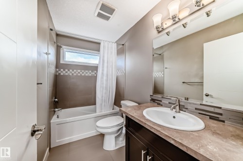 Bathroom featuring a tub/shower combination with full-height tile surround and decorative accent band - 12118 125 Street Nw, Edmonton, AB - Indoor Photo Showing Bathroom