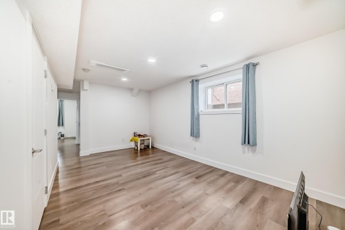 Spacious room featuring wood-finish flooring, recessed lighting, and a window with light-colored drapes - 12118 125 Street Nw, Edmonton, AB - Indoor Photo Showing Other Room