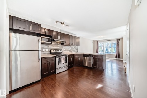 Modern kitchen featuring dark wood cabinetry, stainless steel appliances, a tile backsplash, and light-colored countertops - 12118 125 Street Nw, Edmonton, AB - Indoor Photo Showing Kitchen With Upgraded Kitchen