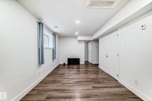 Spacious interior featuring wood-finish flooring, recessed lighting, white trim, and multiple white doors - 12118 125 Street Nw, Edmonton, AB - Indoor Photo Showing Other Room