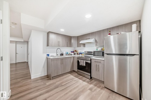 Modern kitchen featuring wood-finish cabinetry, stainless steel appliances, and a white tile backsplash - 12118 125 Street Nw, Edmonton, AB - Indoor Photo Showing Kitchen
