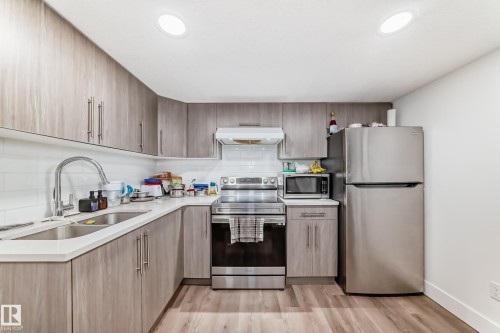 Contemporary kitchen featuring wood-finish cabinetry and stainless steel appliances - 12118 125 Street Nw, Edmonton, AB - Indoor Photo Showing Kitchen With Double Sink